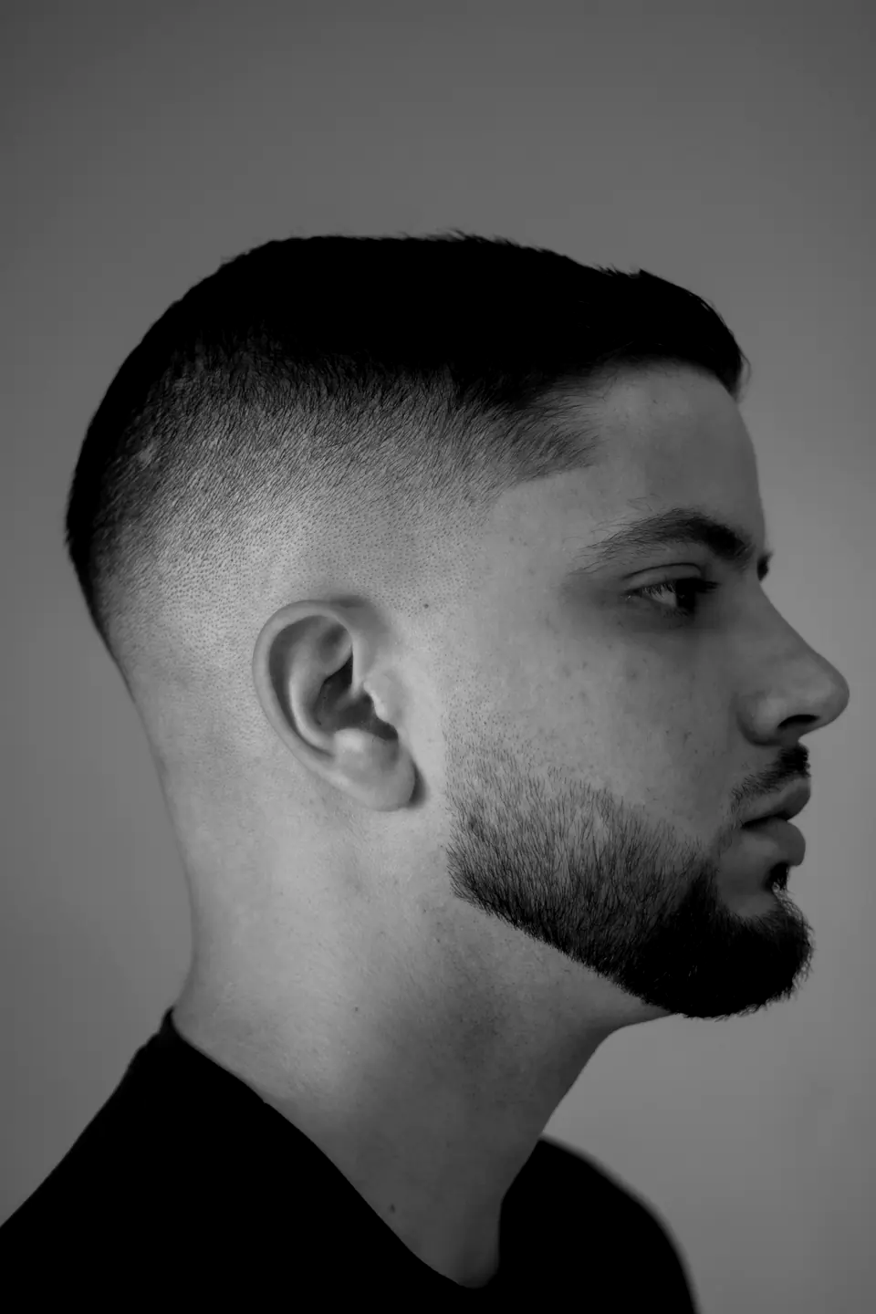 Schwarzweißfoto im Profil: Mann mit Taper Fade und Kinnbart (Beispielbild)