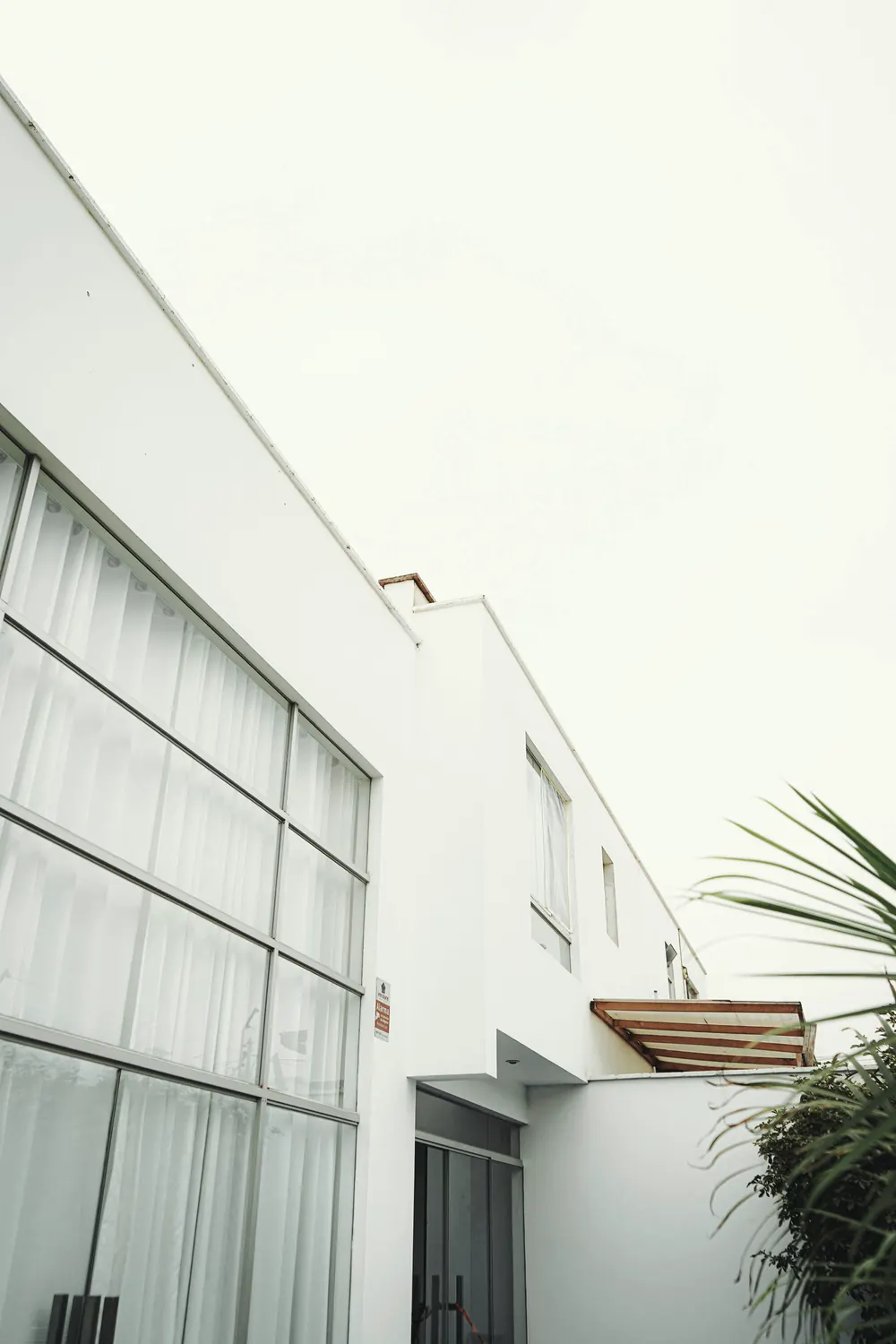 Weiße Fassade mit raumhohen Fenstern und Vorhängen