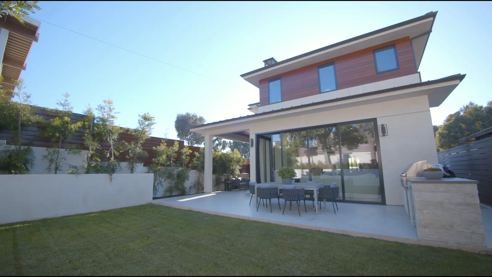 Moderner Neubau von der Gartenseite: heller Putz, großer Glasanteil, Terrasse mit Sitzgruppe