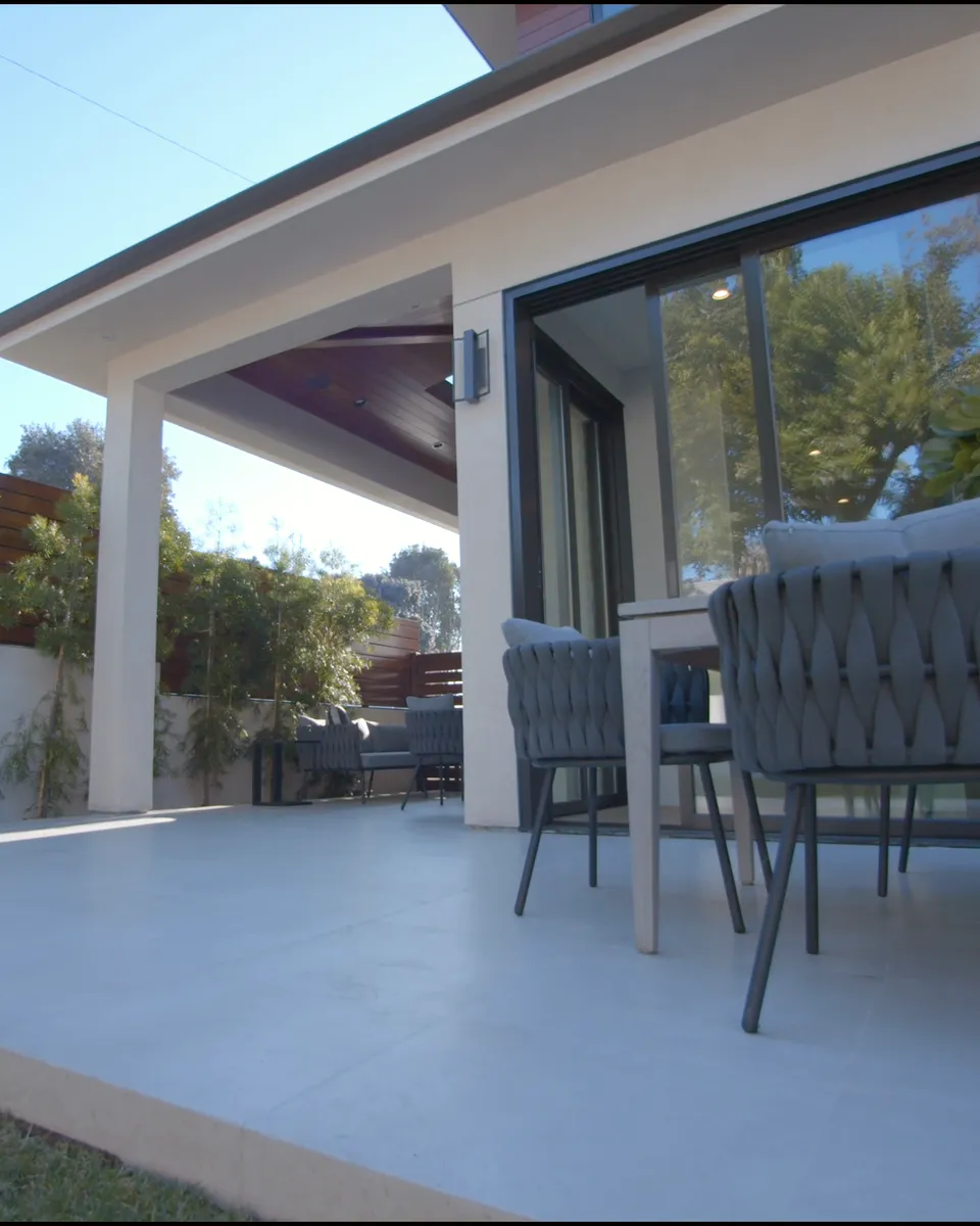 Überdachte Terrasse mit Holzuntersicht, Natursteinwand und bodentiefen Schiebetüren