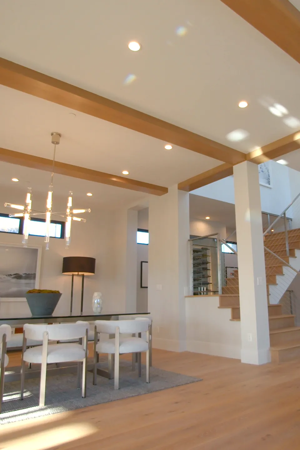 Wohnraum mit Holzbalkendecke, Esstisch und offener Treppe