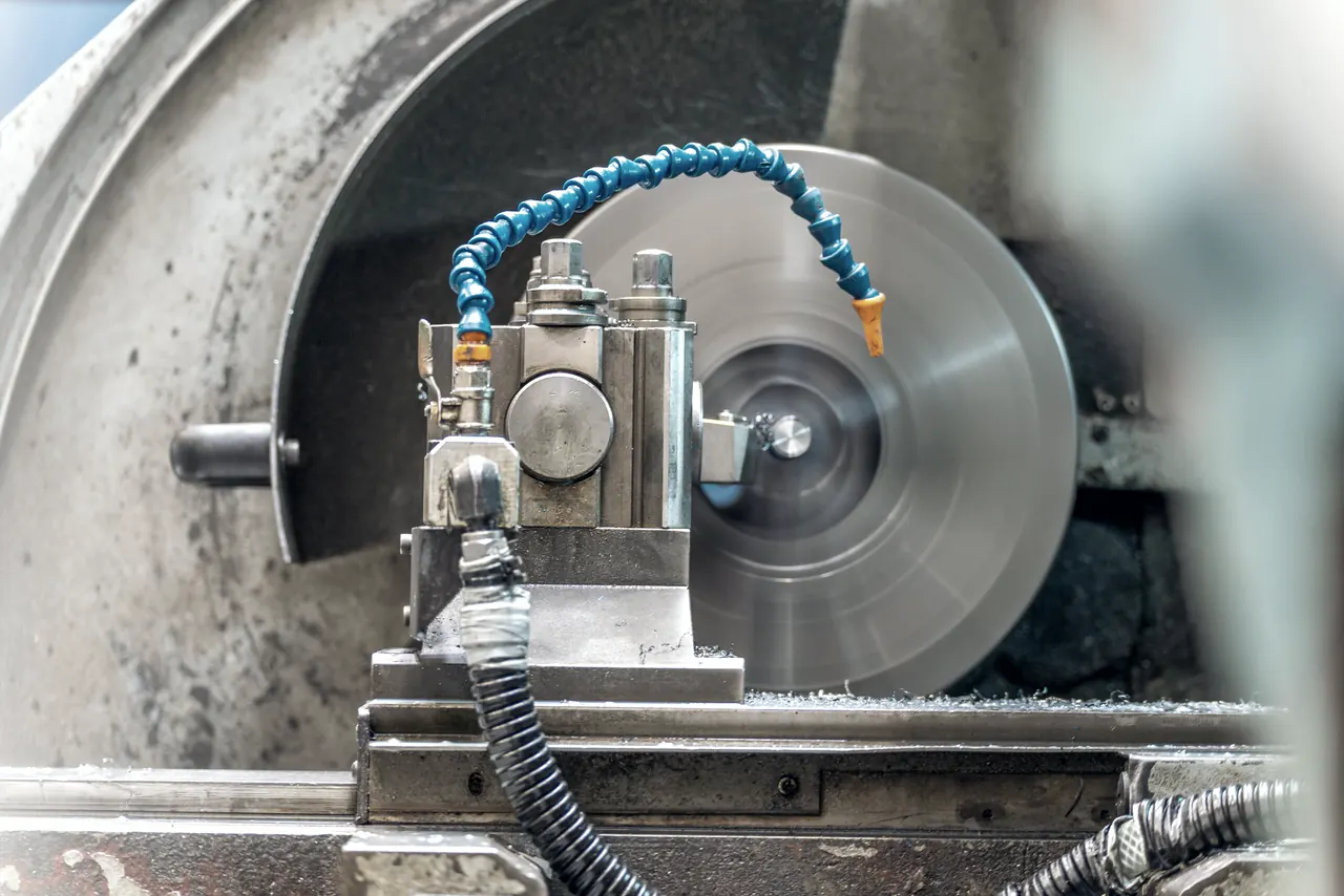 Drehmaschine, bei der ein Werkzeug mit blauem Kühlmittelschlauch an einem rotierenden Werkstück arbeitet