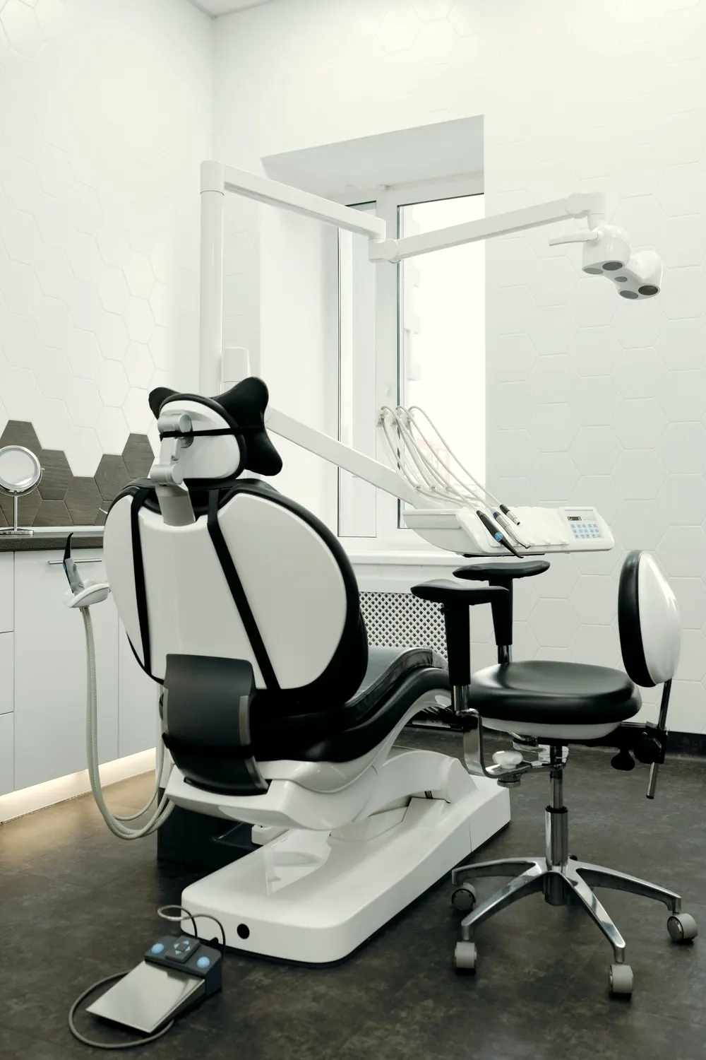 Heller Behandlungsraum mit Liegesessel, Hocker und Fenster