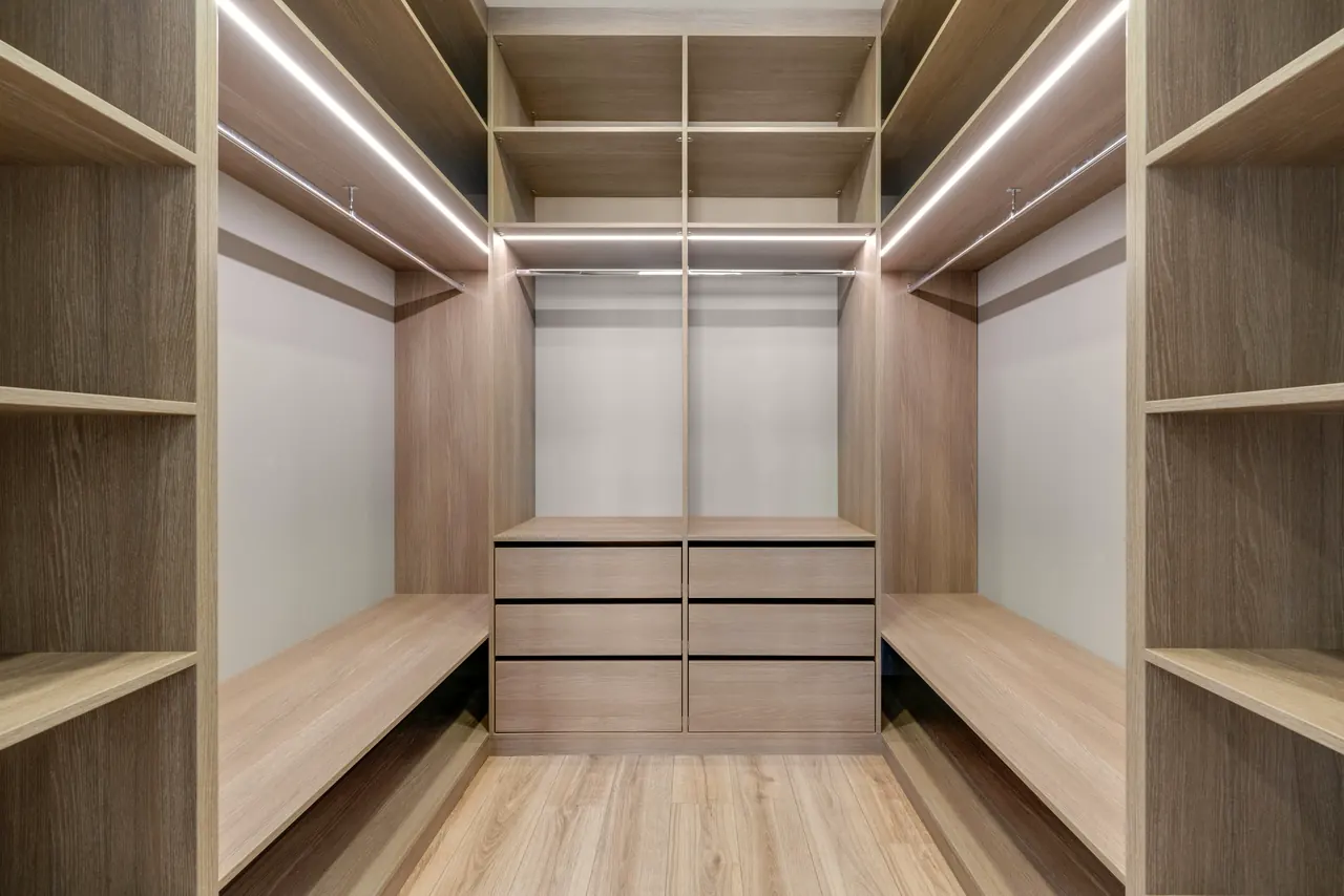 Begehbarer Kleiderschrank aus hellem Holz mit Beleuchtung in den Regalkanten