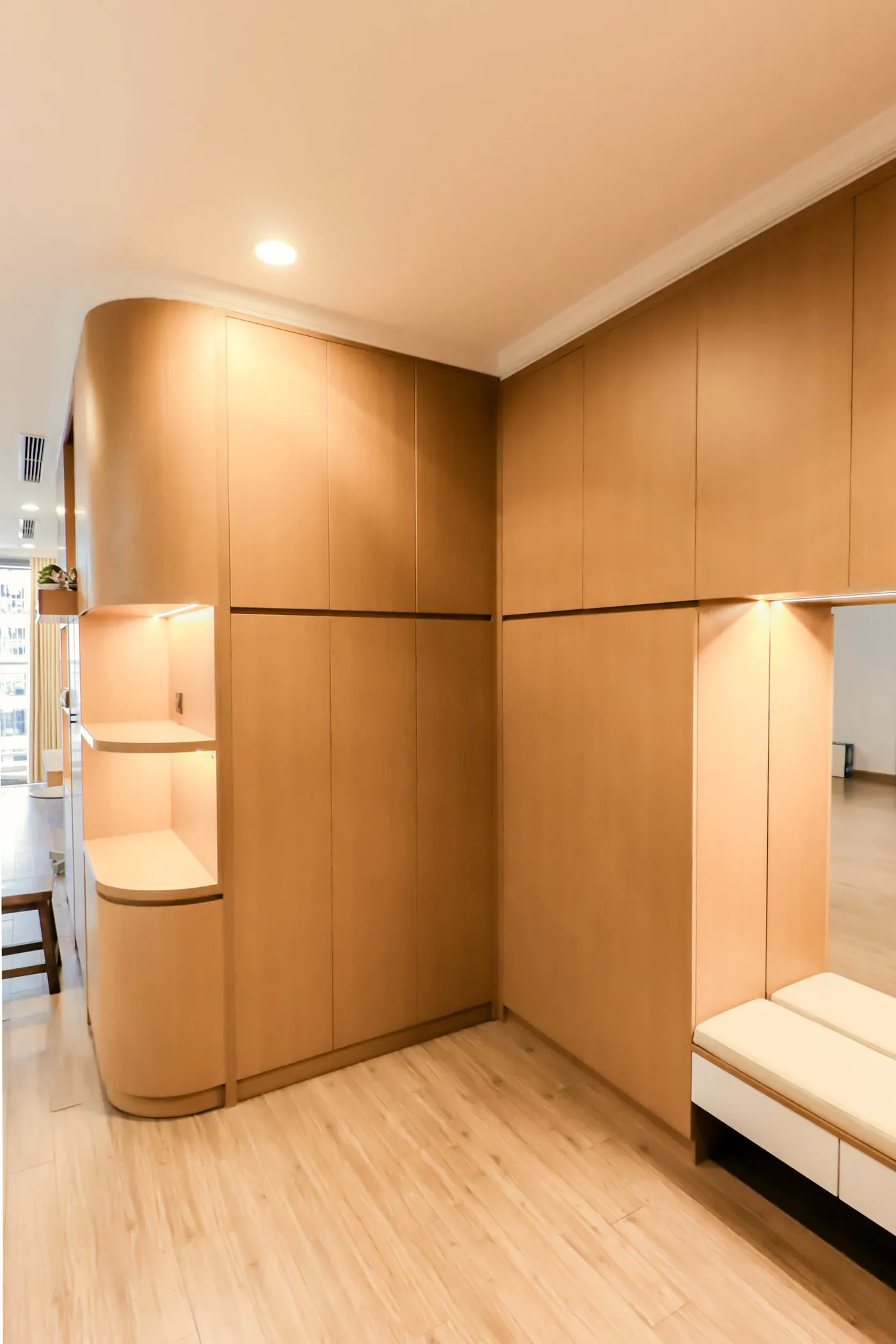 Eingebauter Schrank aus hellem Holz mit abgerundeter Ecke und beleuchteter Nische